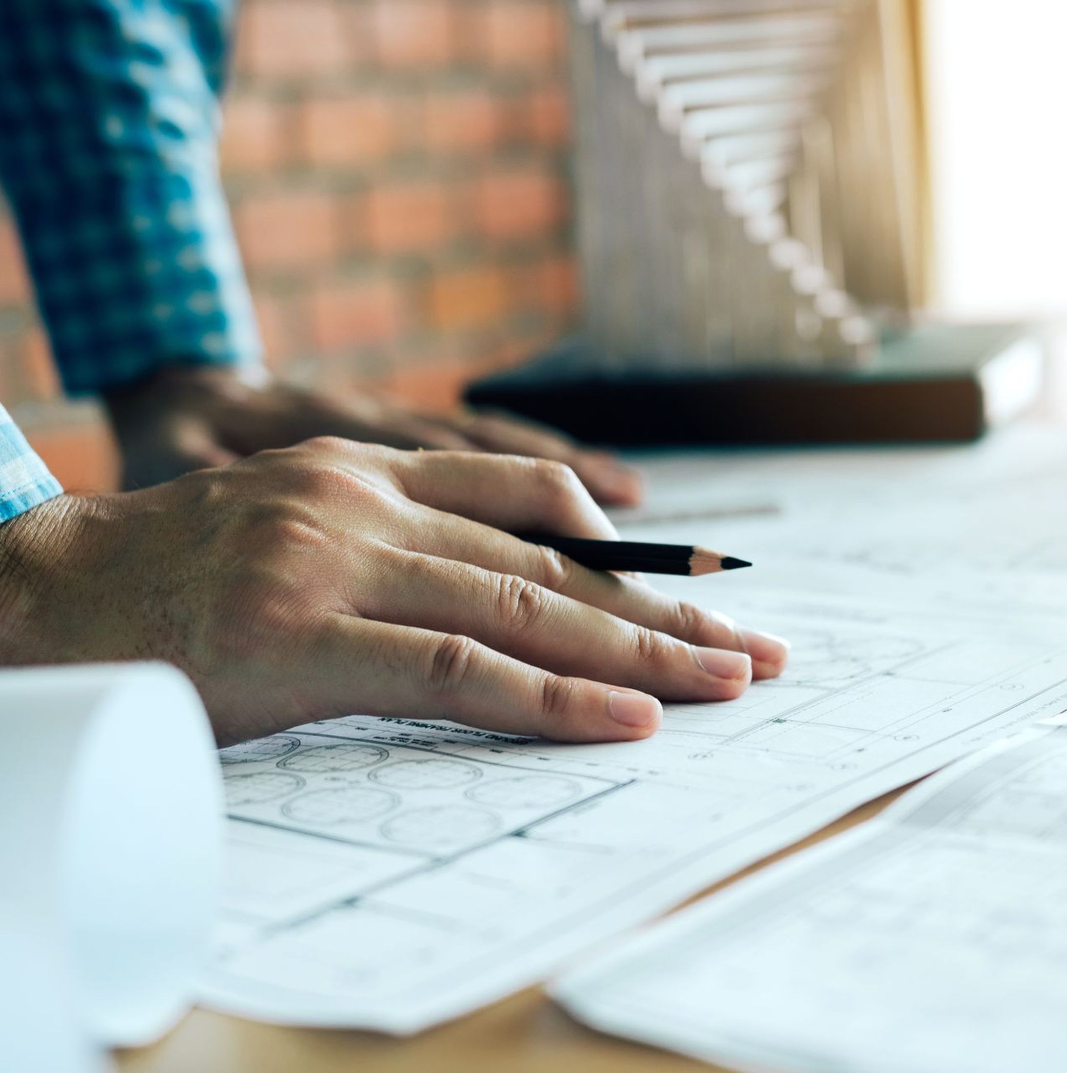 Hand of young engineering man drawing on blueprint with model on